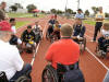 Disabled veterans huddle around to pick up some pointers from experienced wheelchair racers. The man in red (with his back towards the camera) has been racing for many years.
